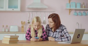 Blonde preteen school girl teaches young mother dancing modern dance for popular social network. 30s woman learning how to record video for social media application.