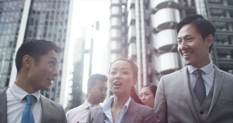 4K Portrait of young Asian business group chatting as they walk through city