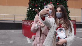 Young women in medical mask talking on video call for Christmas greetings. Xmas holidays in new coronavirus reality.