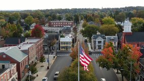 Patriotic American flag waves over small town in USA. Descending drone shot. Cinematic aerial. - Powered by Shutterstock - Get 15% off with code: PIKWIZARD15