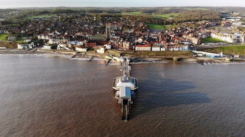 Drone footage from the sea flying over the pier at Cromer, Norfolk towards the town in early morning.