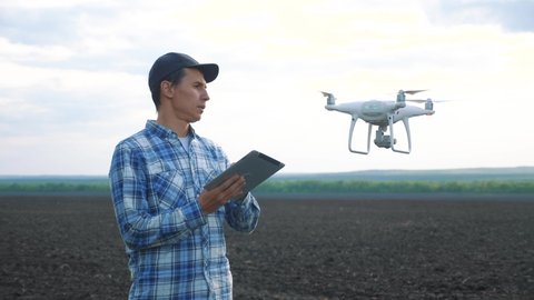 agriculture. smart farming tech farming. man farmer engineer studies a farmland in black mud dirt field using a technology quadcopter. male red worker neck works in a green in lifestyle field of corn