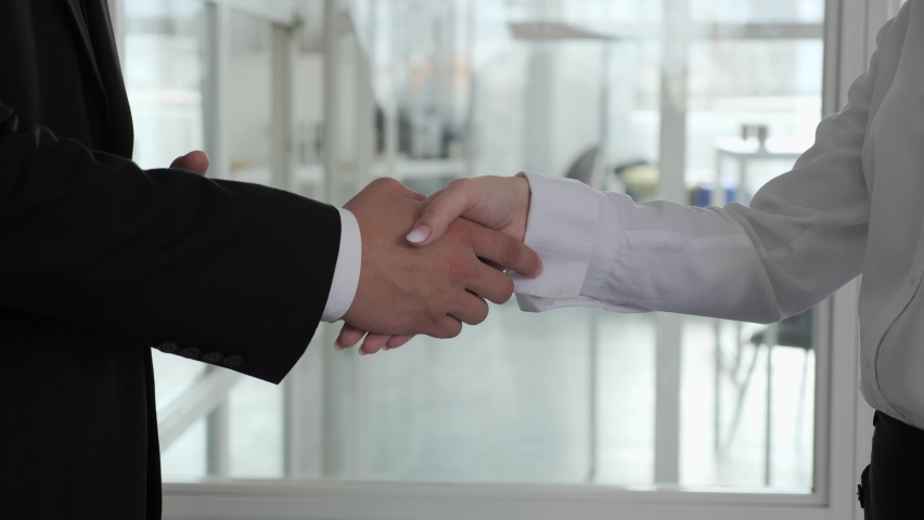 Close up Hand of two caucasian business people gathered to handshake agree to a deal or say hello in the office | Shutterstock HD Video #1062249136