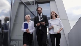 Team of three successful businessmen with laptop and documents confidently walk on the terrace talking and laughing - Powered by Shutterstock - Get 15% off with code: PIKWIZARD15