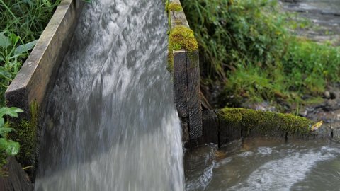 Slow Motion Water flows through a wooden gutter
