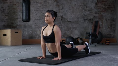Sport woman training stretching in fitness mat in gym club. Flexible fitness woman stretching muscles for splits on mat in sport club