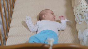 Newborn baby boy lying in bed. Calm cute funny baby wearing pajamas closeup. Naptime