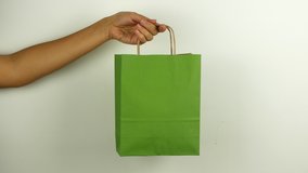 A woman holds a green shopping bag in honor of Black Friday and Cyber Monday. 4K video close-up of a package with purchases on the day of discounts.
