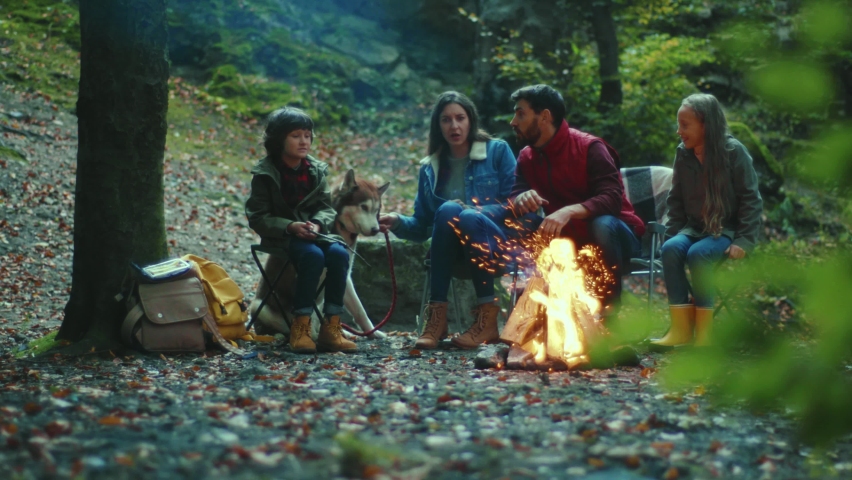 Family sits near campfire on autumn evening tells scary stories. Children with their parents are resting in the woods. Childhood relationship camping. Close up. Slow motion Royalty-Free Stock Footage #1062262207