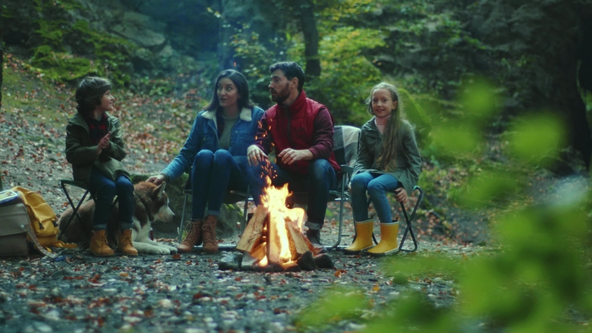 Portrait family sits near campfire on autumn evening. Children with their parents are resting in the woods. Childhood relationship camping. Close up. Slow motion Royalty-Free Stock Footage #1062262216
