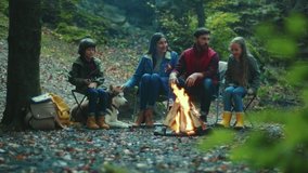 Portrait family sits near campfire on autumn evening. Children with their parents are resting in the woods. Childhood relationship camping. Close up. Slow motion - Powered by Shutterstock - Get 15% off with code: PIKWIZARD15