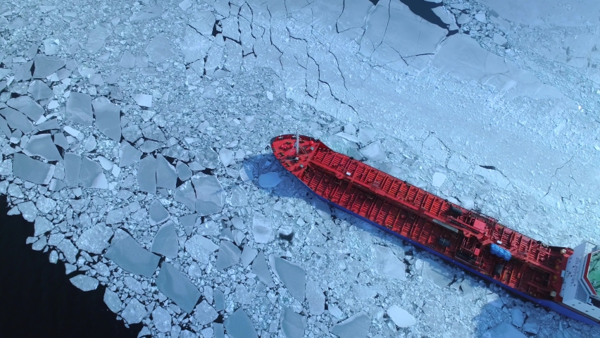 Aerial epic red nuclear icebreaker ship in winter sails through frozen sea makes its way. Ice floe graphic pattern. Specialized vessel for icebreaking operations made an expedition North pole, Arctic