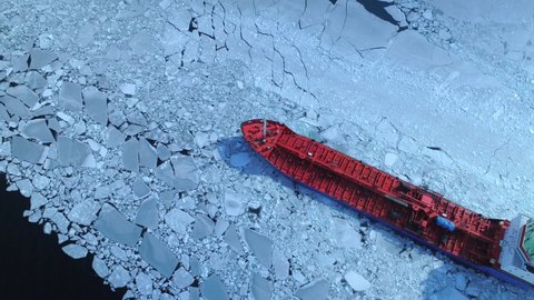 Aerial epic red nuclear icebreaker ship in winter sails through frozen sea makes its way. Ice floe graphic pattern. Specialized vessel for icebreaking operations made an expedition North pole, Arctic