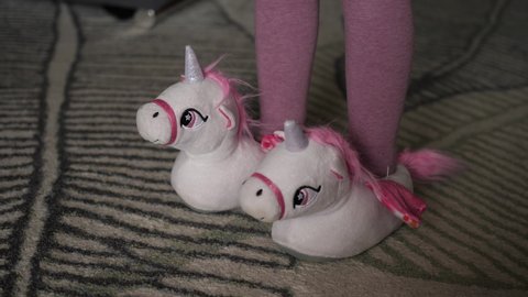 little girl wearing unicorn-shaped slippers unicorns
