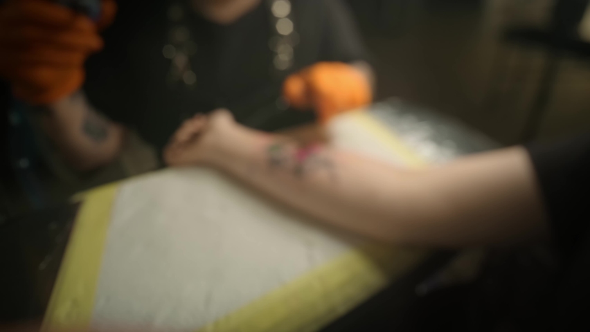 Tattoo artist makes a tattoo woman on a arm, works in studio. Slow motion Wide view Royalty-Free Stock Footage #1062265276