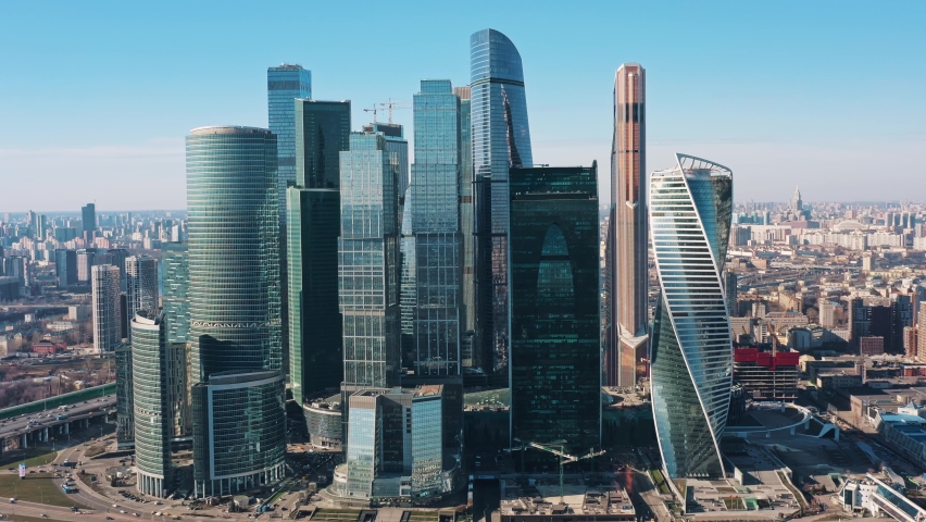Zoom out drone aerial shot of Moscow city skyscrapers in a day time. Drone flying back with a view on Moscow City and glass buildings under bright day sun in spring Royalty-Free Stock Footage #1062268129