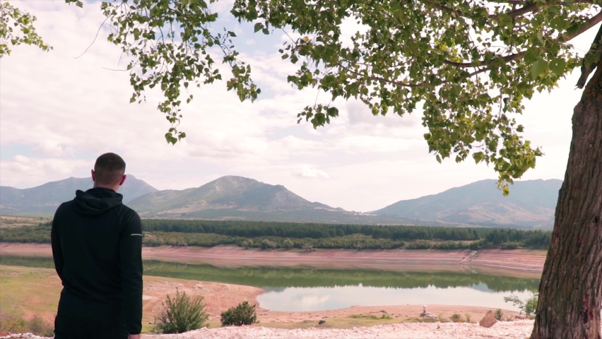 Person walking in nature and enjoying the peaceful environment. Dam and lake.