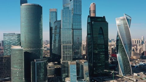 Pan shot left to right of Moscow city skyscrapers in a daylight. Pan shot of drone with a view on Moscow City with glass buildings under bright day sun in spring