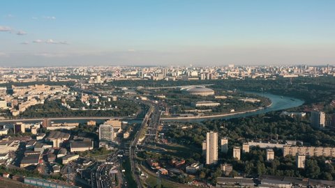 Moscow city landscape drone shot, fly over Moscow centre under bright sky in summer. Moskva river, green trees and Luzhniki shot from above zoom in