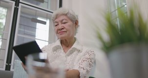 Senior Asian Lady Using Tablet Computer At Home