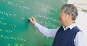 slow motion of asian senior male calculus professor is writing in front of blackboard in the classroom at college
