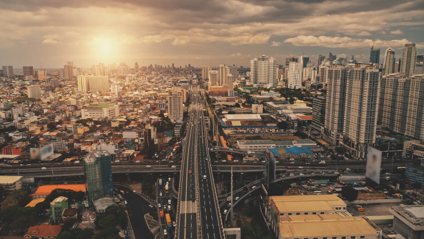 Cityscape at sun light with cross highway, streets, skyscrapers aerial. Bridge traffic road with driving cars at summer sunny day. Philippines capital of Manila town at cinematic drone shot Royalty-Free Stock Footage #1062272704