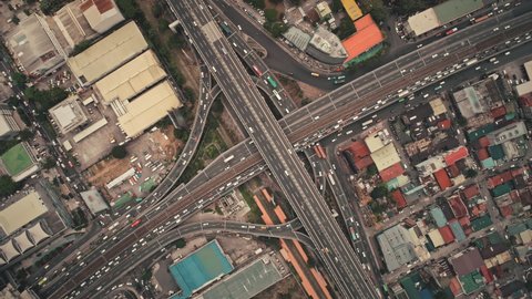 Slow motion top down of cross road traffic with cars, trucks, vehicles in aerial view. Downtown of Manila city with colorful buildings roofs at roadside. Philippines urban lifestyle with local journey