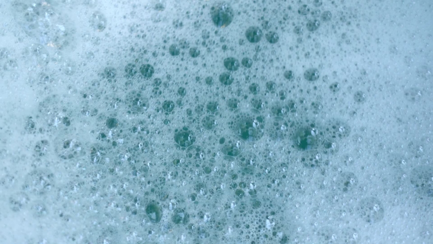 Closeup top view video of foamy surface of clean water. Abstract foamy background.