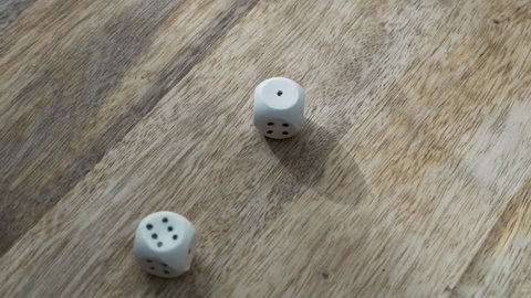 Entertainment Game Concept. A Hand Throws Two Dice on a Wooden Table. Close-up of Rotating Cubes and Fingers.