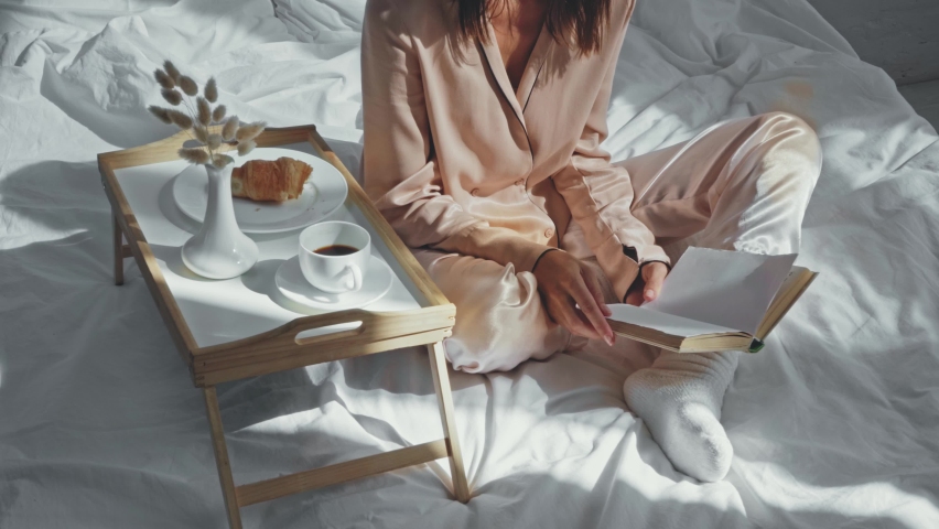cropped view of woman drinking coffee and reading book in bed Royalty-Free Stock Footage #1062282277