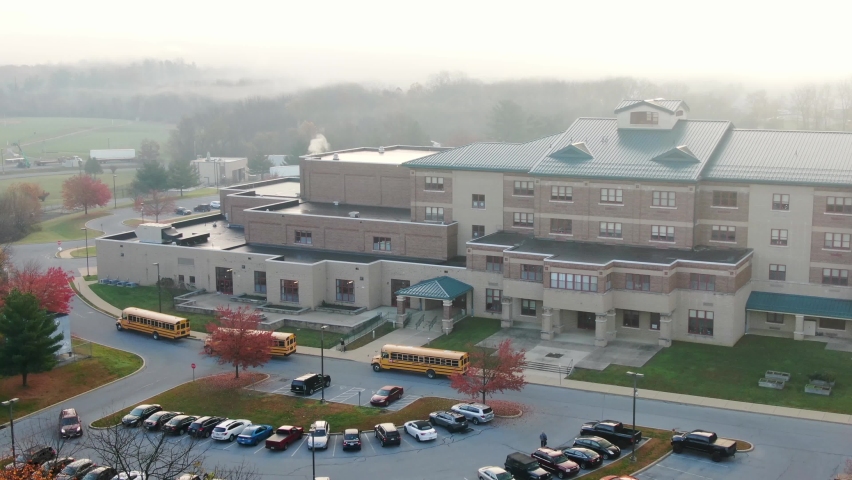 Foggy, misty hazy morning at school building. Bus line up for students. Smoke coming from chimney of modern academic building. Royalty-Free Stock Footage #1062287350