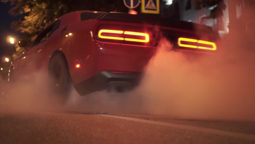 Car start with smoke on wheels. Footage. Red modern drag sport auto burning tire at city street. | Shutterstock HD Video #1062290047