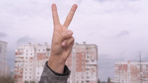 Woman show peace sign. A view of a woman's hand showing a peace sign on a blue sky background.