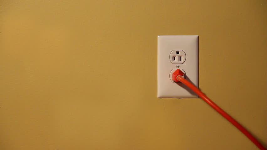 Close-up shot of a man plugging and unplugging an orange electrical cord into a