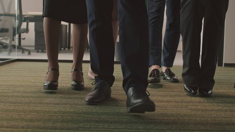 Medium shot of legs of unrecognizable business people going together in the office