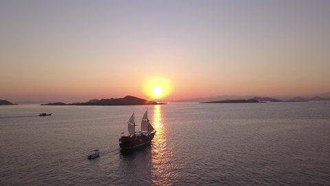 Sailing komodo in the middle of national komodo park sea during the sunrise with drone view