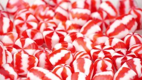 Red and White Striped Candy Falling on a Sweets Pile in Slow Motion as Perfect Unhealthy Food Background. Tasty Desserts in Motion. Christmas and New Year Symbol