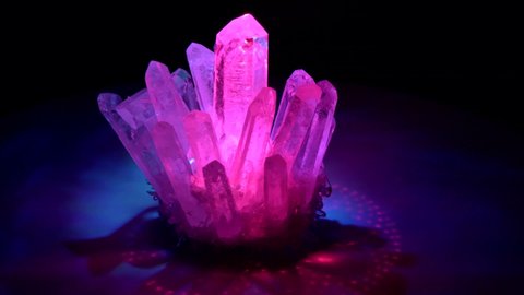 Rhinestone crystal rotates around in colored laser beams. Large crystals of natural transparent stone rock crystal close-up, transparent quartz in crystals, geology, magical rites and esotericism.