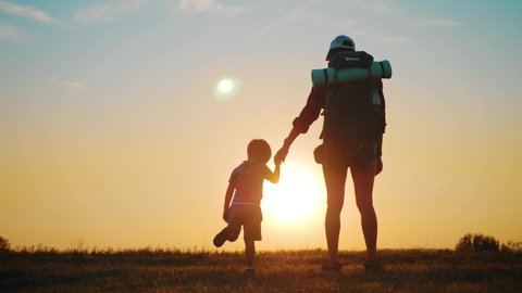 Mother with little boy hiking adventure with child on family trip. A woman with a backpack is traveling with child. Hike with kids at sunset.
