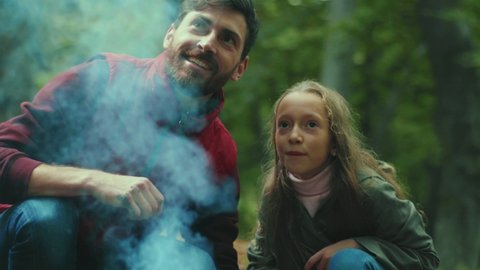 Happy father and daughter in the woods sets up campfire sticks. Talking smiling. Family time. Forest happiness nature fire. Close up. Slow motion