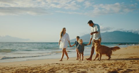 Happy young family playing with adorable golden retriever on the beach