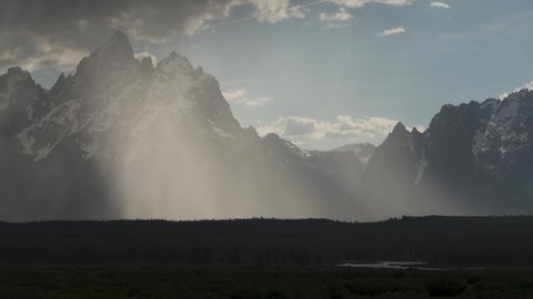 Timelapes from of cloudy and snowy Grand Tetons in Grand Teton National Park with storm clearing and reflection in clouds, Wyoming  