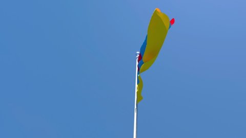 The national flag of Armenia is flying in the wind against a blue sky