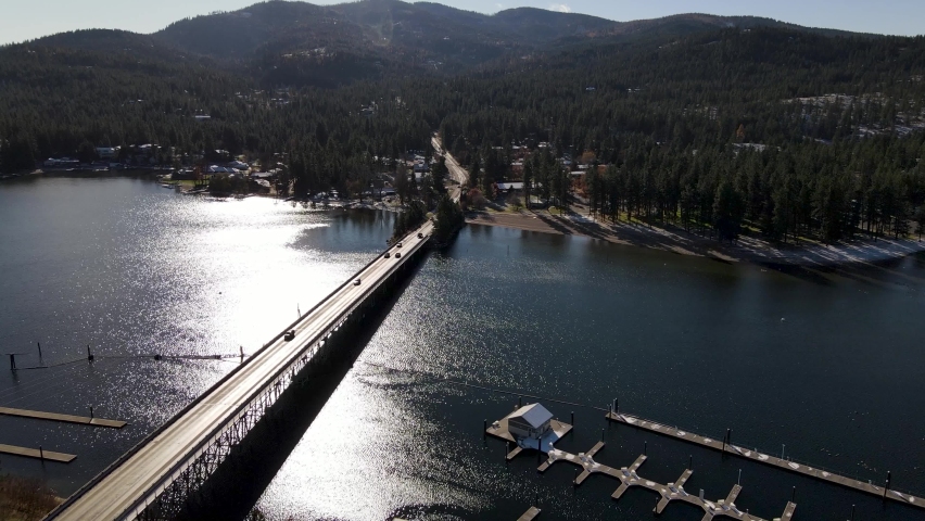 Bridge with traffic crossing the Spokane River into a neighborhood of homes with mountains in the background on a sunny day in Post Falls Idaho.
