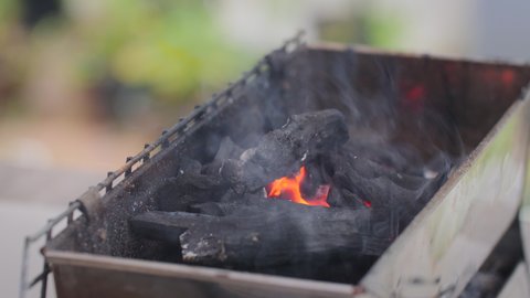 Close-up shot set a fire in the barbeque grill by wooden carbon charcoal with smoke, selective focus shallow depth of field