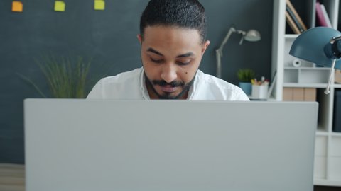 Slow motion of elegant mixed race man office worker using computer at work sitting at desk and typing looking at screen. People and job concept.
