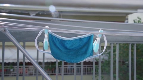 One washed reusable face mask hanging on clothes dryer with clothespin.