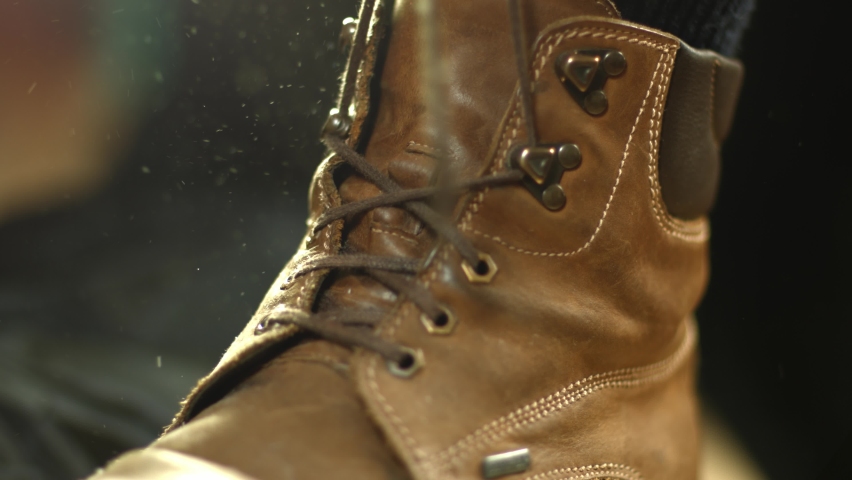 Leather hiking boots (bootlace) being tied by a person while dust particles fly around in the bright morning sun light. Close up cinematic shot. Royalty-Free Stock Footage #1062349207