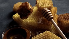 Honey dipper on the bee honeycomb on black table. Horizontal composition 4K UHD video footage