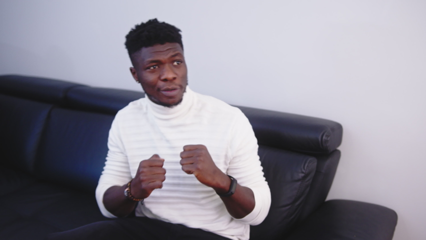 Young black man watching sport competition on tv. Boxing match. High quality 4k footage